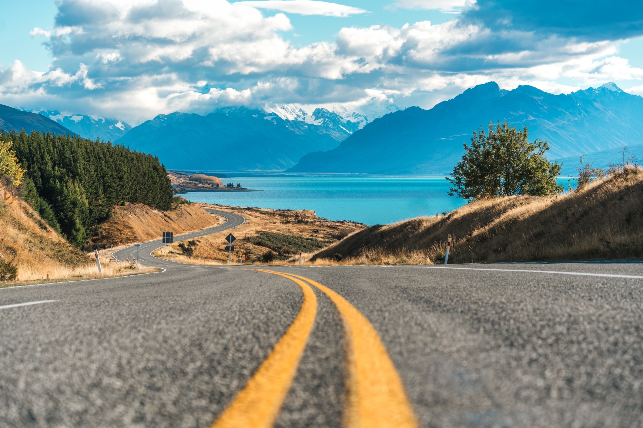 Scenic asphalt winding road leading to Mount Cook or Aoraki and Lake Pukaki during autumn on sunny day at Peters lookout, New Zealand.