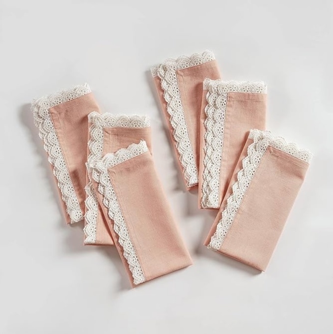 Pile of light pink cloth napkins with white lace trim