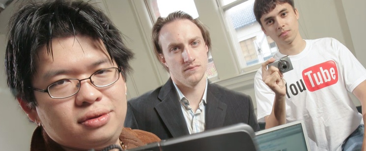 A historic photo of YouTube co-founders Steve Chen, Chad Hurley, and Jawed Karim looking at a laptop together.