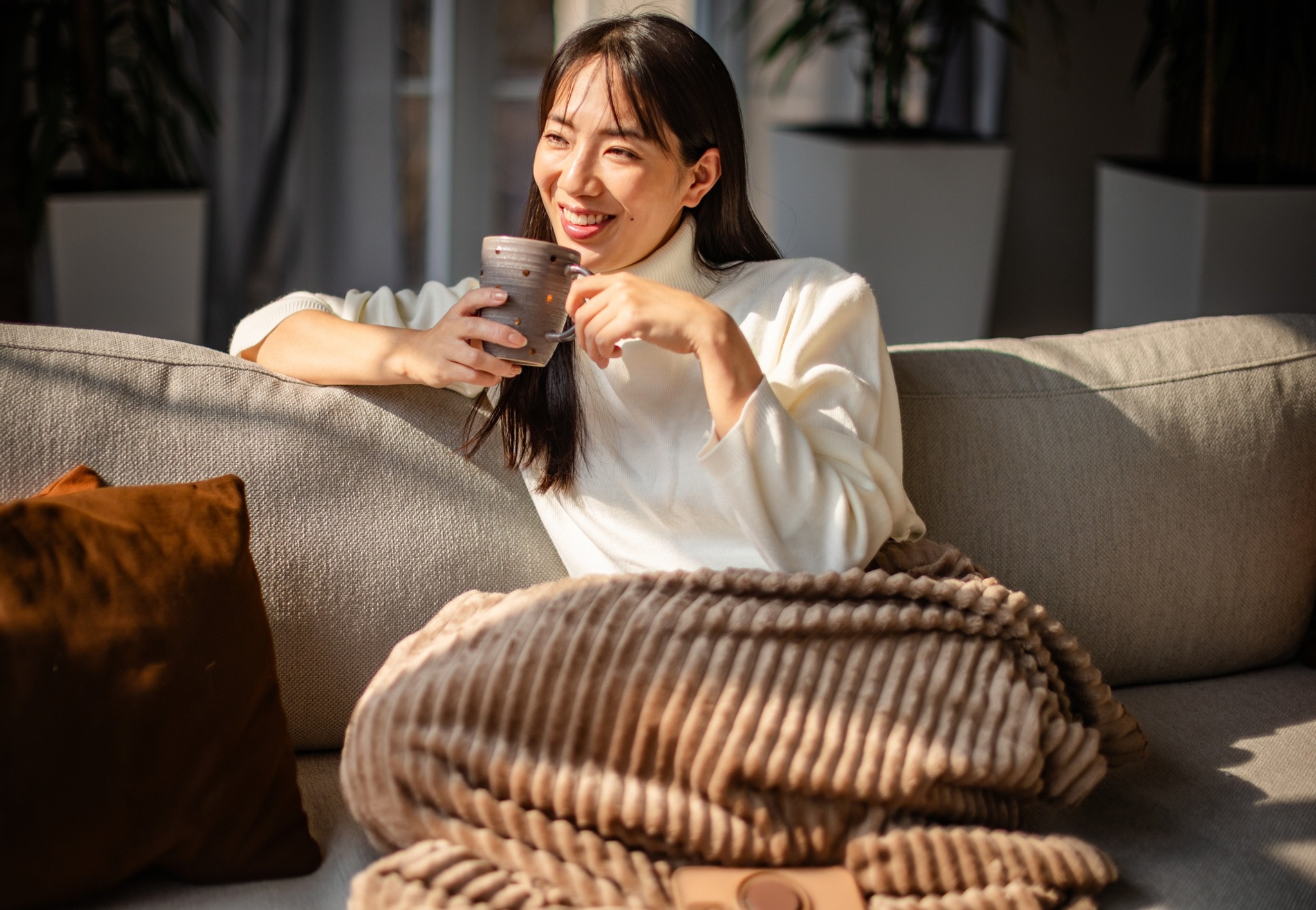 Woman smiling drinking coffee on the couch