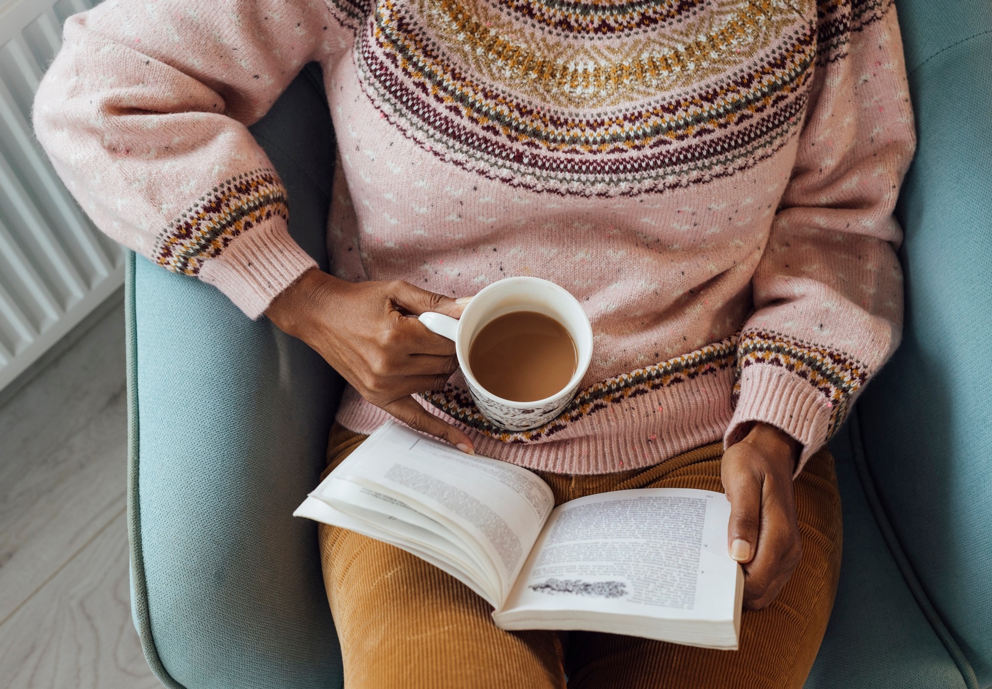 Person holding coffee and reading a book