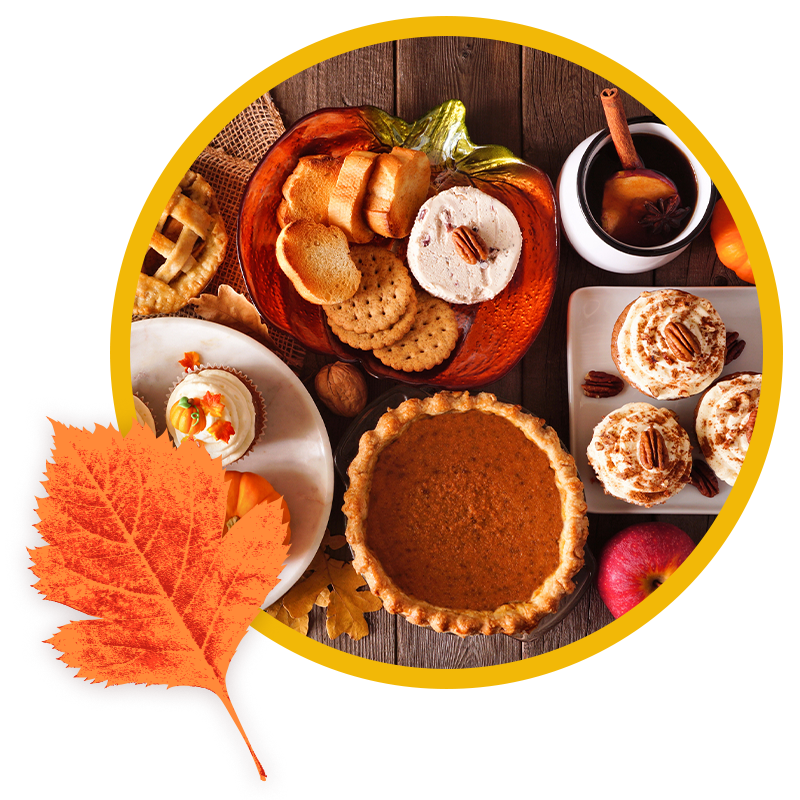 An overhead spread of fall desserts including a whole pumpkin pie, frosted pumpkin cupcakes, mini pies, crackers with dip served in a carved pumpkin, and mulled cider, next to a fall leaf graphic.