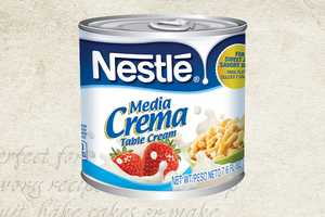 Nestlé Media Crema can against a textured background with handwritten recipe text. / Lata de Nestlé Media Crema sobre un fondo texturizado con texto de receta escrito a mano.