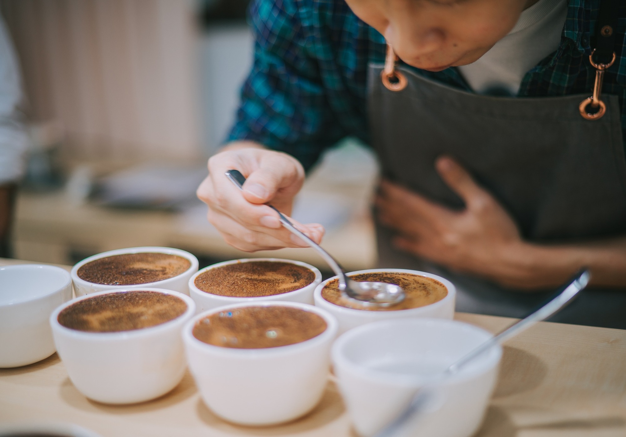 Person tasting coffee with several cups in front of them