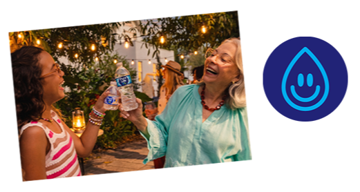 Woman and girl smiling and raising bottles of Pure Life water at an evening outdoor gathering.
