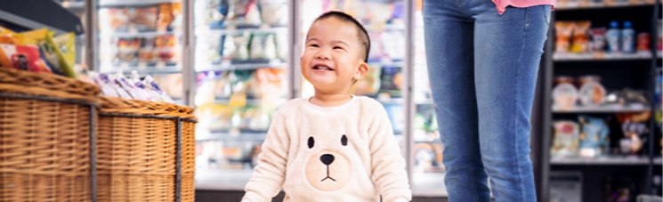 Toddler walking in grocery store with parent.