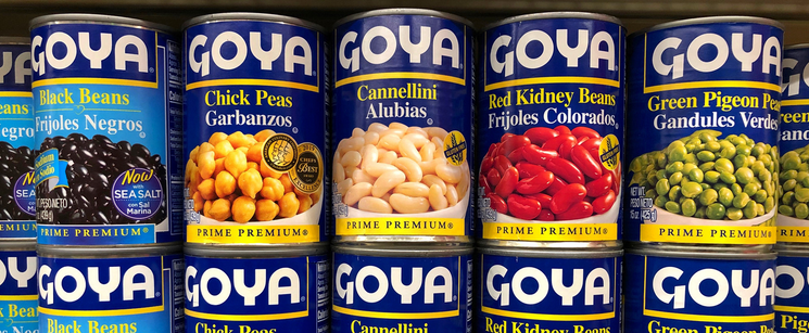 Shelves stacked with various canned beans from Goya, including black beans, chickpeas, cannellini, and red kidney beans.