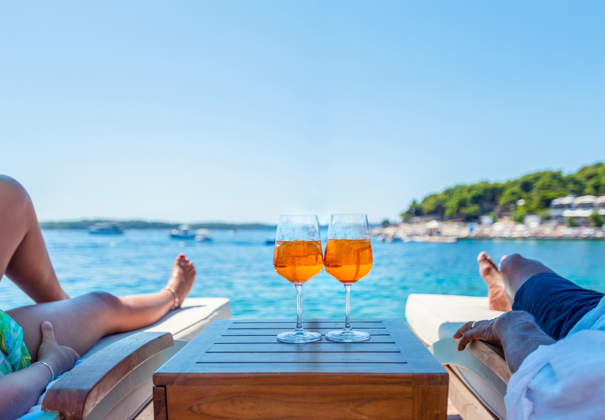 2 people enjoying Aperol Spritzes by the water