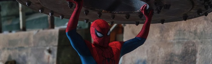 Spider-Man in his suit lifting heavy metal debris above his head.