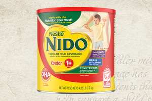 Nestlé NIDO Kinder 1+ Toddler Milk Beverage can against a textured background with handwritten recipe text. / Lata de Nestlé NIDO Kinder 1+ Toddler Milk Beverage sobre un fondo texturizado con texto de receta escrito a mano. 