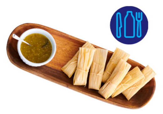 Tamales served on a wooden platter with a bowl of green salsa.
