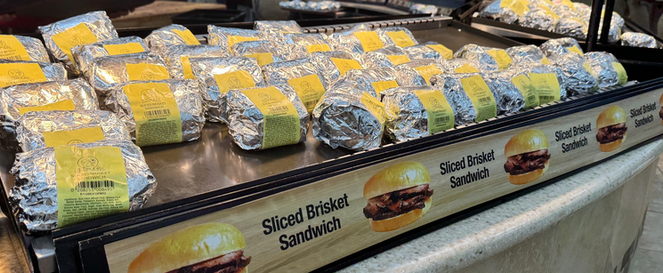 Display of wrapped sliced‑brisket sandwiches.